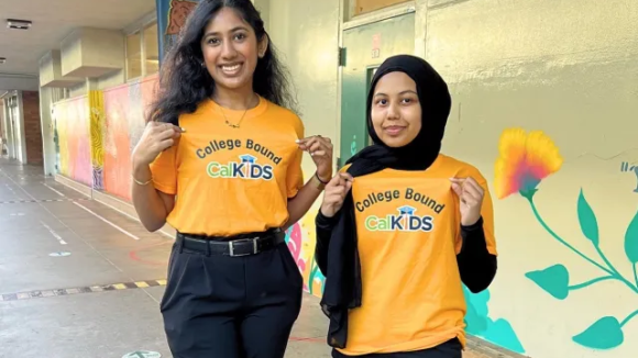 Two students stand smiling wearing yellow shirts that read "College Bound CalKIDS"