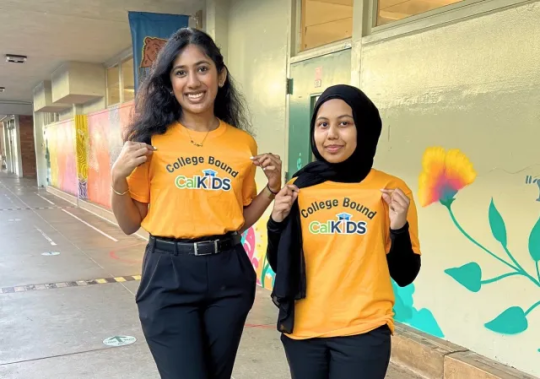 Two students stand smiling wearing yellow shirts that read "College Bound CalKIDS"